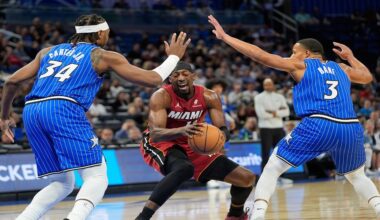 Miami Heat center Bam Adebayo, center, stops short as Orlando Magic center Wendell Carter Jr. (34) and guard Desmond Bane (3) block the path to the basket during the first half of an NBA basketball game, Friday, Dec. 5, 2025, in Orlando, Fla. (AP Photo/John Raoux)