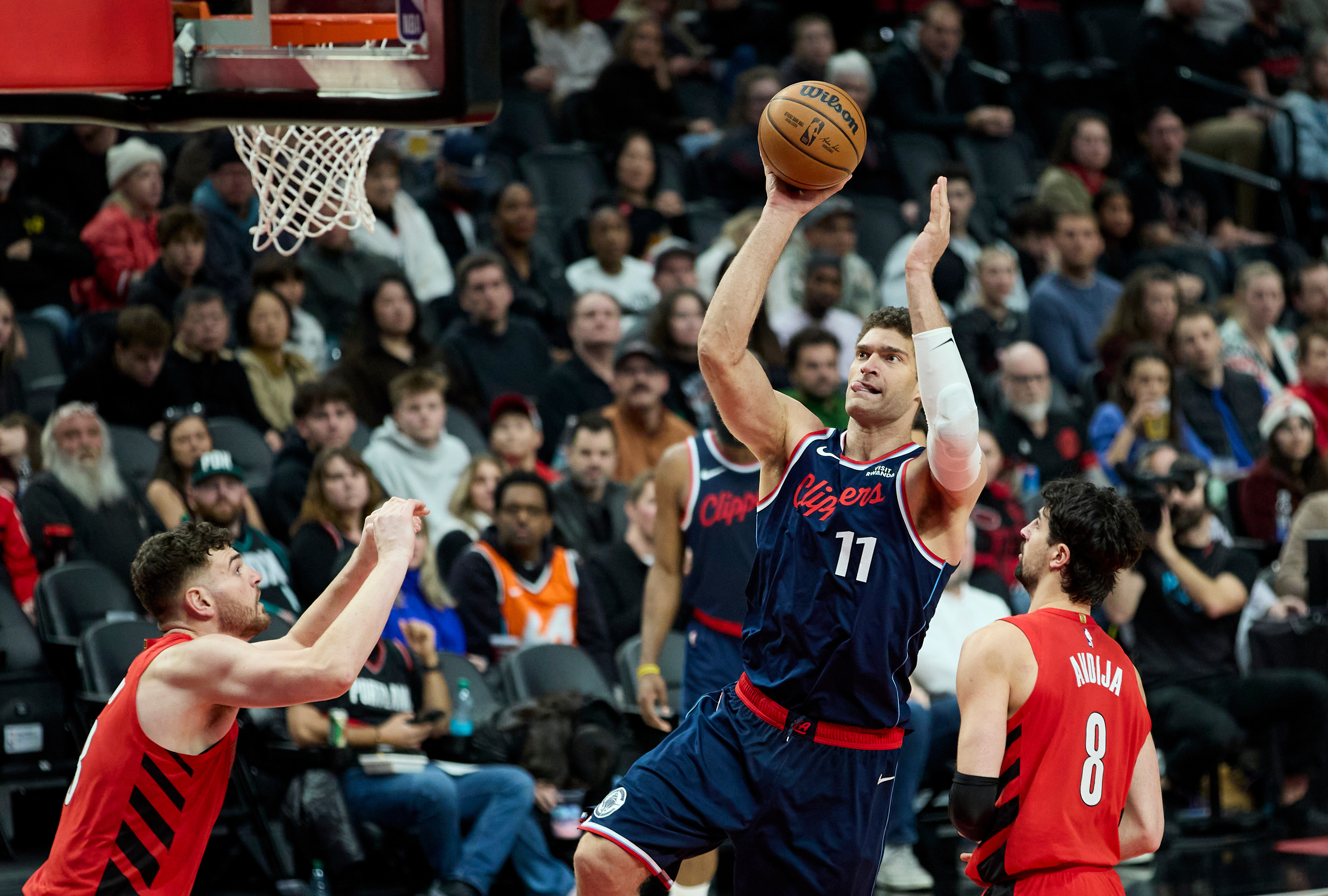 Clippers center Brook Lopez, center, shoots between Portland Trail Blazers...