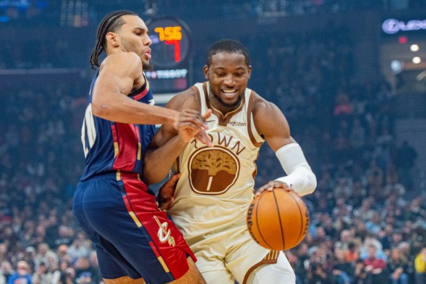 Golden State Warriors' Jonathan Kuminga, right, drives against Cleveland Cavaliers' Jaylon Tyson, left, during the first half of an NBA basketball game in Cleveland, Saturday, Dec. 6, 2025. (AP Photo/Phil Long)