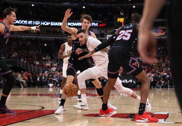 Cleveland Cavaliers guard Lonzo Ball (2) tries to drive through the defense of Chicago Bulls forward Matas Buzelis (14) and forward/center Jalen Smith (25) in the first half of a game at the United Center in Chicago on Dec. 17, 2025. (Chris Sweda/Chicago Tribune)