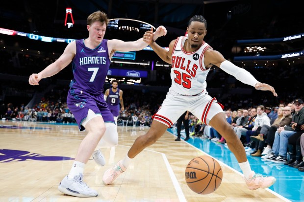 Bulls forward Isaac Okoro (35) and Hornets guard Kon Knueppel battle for a loose ball during the second half Friday, Dec. 12, 2025, in Charlotte, N.C. (Nell Redmond/AP)