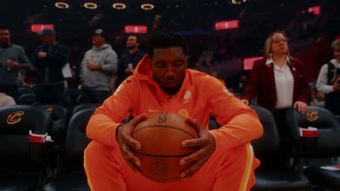 Donovan Mitchell sits and holds the basketball with his eyes closed.