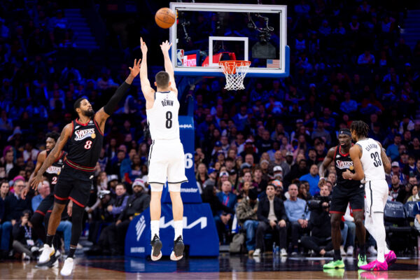 Brooklyn Nets' Egor Demin, center, shoots the three point shot as Philadelphia 76ers' Paul George, left, defending during the second half of an NBA basketball game, Tuesday, Dec. 23, 2025, in Philadelphia. (AP Photo/Chris Szagola)