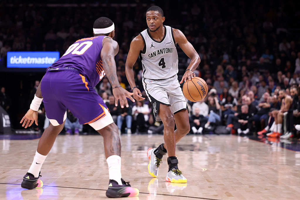 PHOENIX, ARIZONA - NOVEMBER 23: De'Aaron Fox #4 of the San Antonio Spurs dribbles the ball against Royce O'Neale #00 of the Phoenix Suns during the first half at Mortgage Matchup Center on November 23, 2025 in Phoenix, Arizona. The Suns defeated the Spurs 111-102. NOTE TO USER: User expressly acknowledges and agrees that, by downloading and or using this photograph, User is consenting to the terms and conditions of the Getty Images License Agreement. (Photo by Chris Coduto/Getty Images)