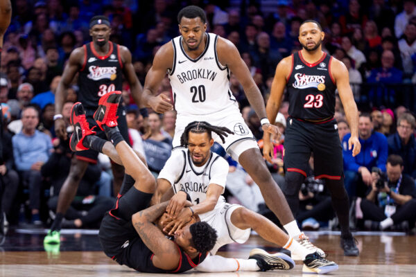 Philadelphia 76ers' Justin Edwards, left, battles for the loose ball with Brooklyn Nets' Ziaire Williams, middle, as Day'Ron Sharpe, top, watches during the second half of an NBA basketball game, Tuesday, Dec. 23, 2025, in Philadelphia. (AP Photo/Chris Szagola)