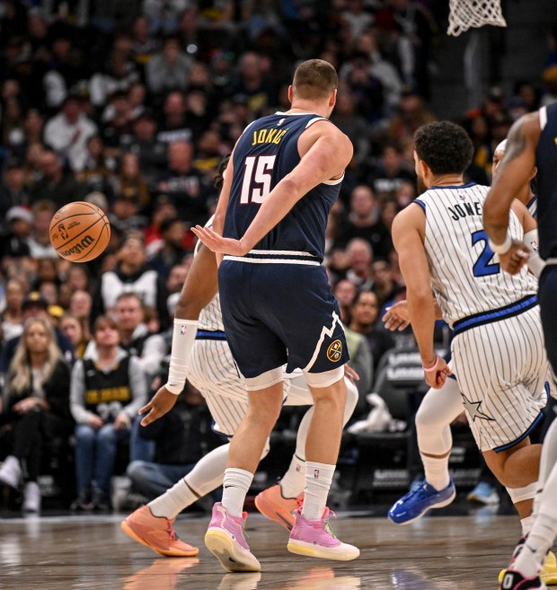 DENVER , CO - DECEMBER 18: Nikola Jokic (15) of the Denver Nuggets passes behind his back as Tyus Jones (2) of the Orlando Magic watches during the third quarter at Ball Arena in Denver, Colorado on Thursday, December 18, 2025. (Photo by AAron Ontiveroz/The Denver Post)