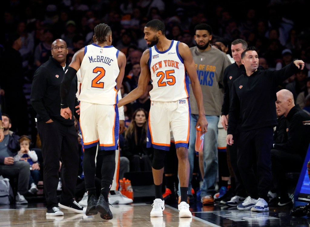 New York Knicks guard Miles McBride limps off the court toward the locker room while being consoled by his teammates.