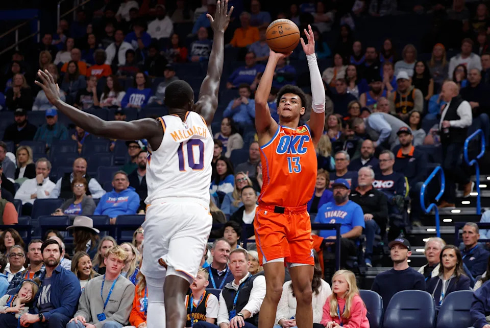 Dec 10, 2025; Oklahoma City, Oklahoma, USA; Oklahoma City Thunder forward Ousmane Dieng (13) shoots a three point basket as Phoenix Suns center Khaman Maluach (10) defends during the second half at Paycom Center. Mandatory Credit: Alonzo Adams-Imagn Images