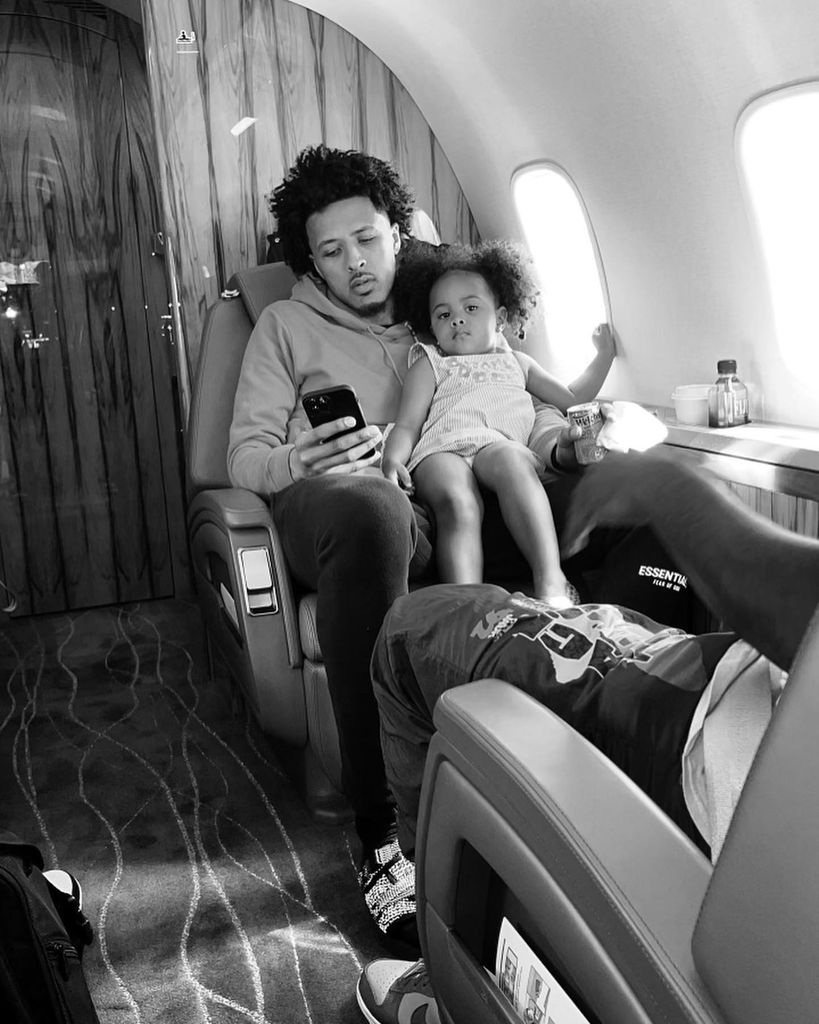 black and white photo of cade cunningham holding daughter on lap on private plane