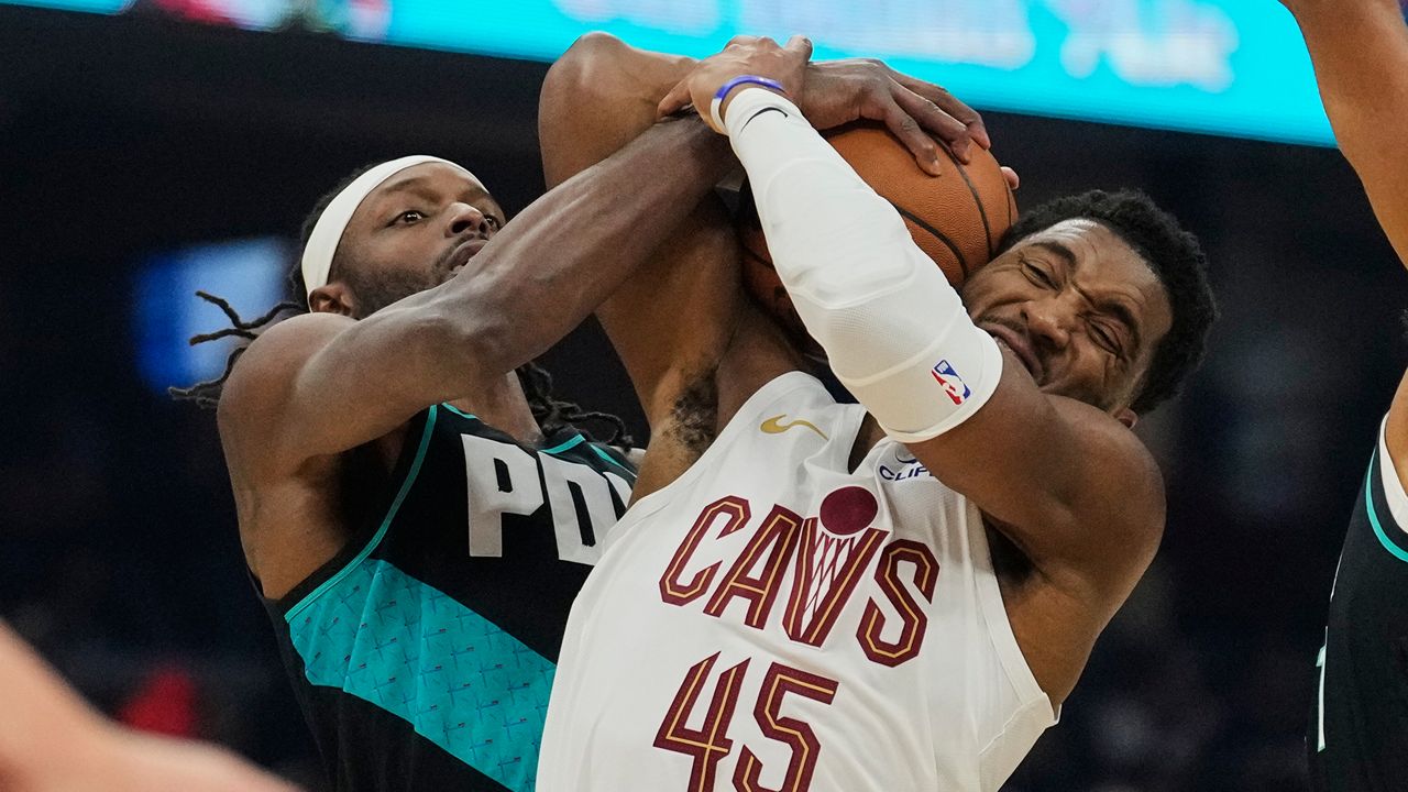 Portland Trail Blazers forward Jerami Grant, left, and Cleveland Cavaliers guard Donovan Mitchell (45) fight for control of the ball in the first half of an NBA basketball game Wednesday, Dec. 3, 2025, in Cleveland. (AP Photo/Sue Ogrocki)