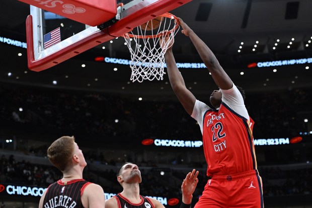 New Orleans Pelicans' Derik Queen dunks over Chicago Bulls' Nikola Vučević, center, and Kevin Huerter, left, on Sunday, Dec. 14, 2025, in Chicago. (AP Photo/Paul Beaty)