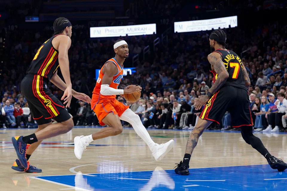 Dec 29, 2025; Oklahoma City, Oklahoma, USA; Oklahoma City Thunder guard Shai Gilgeous-Alexander (2) drives to the basket between Atlanta Hawks guard Nickeil Alexander-Walker (7) and Atlanta Hawks forward Asa Newell (14) during the second half at Paycom Center. Mandatory Credit: Alonzo Adams-Imagn Images