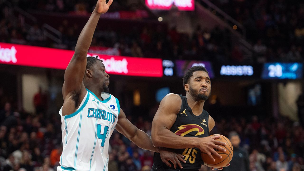 Cleveland Cavaliers' Donovan Mitchell (45) keeps the ball away from Charlotte Hornets' Sion James (4) during the second half of an NBA basketball game in Cleveland, Sunday, Dec. 14, 2025. (AP Photo/Phil Long)