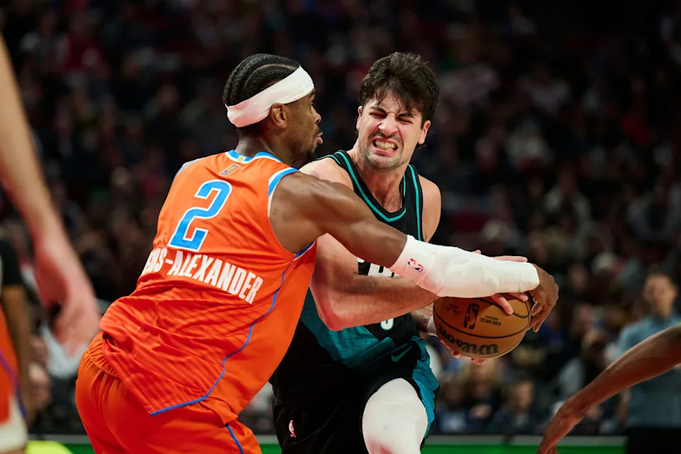 Nov 30, 2025; Portland, Oregon, USA; Portland Trail Blazers forward Deni Avdija (8) is fouled by Oklahoma City Thunder guard Shai Gilgeous-Alexander (2) as he drives to the basket during the second half at Moda Center. Mandatory Credit: Troy Wayrynen-Imagn Images