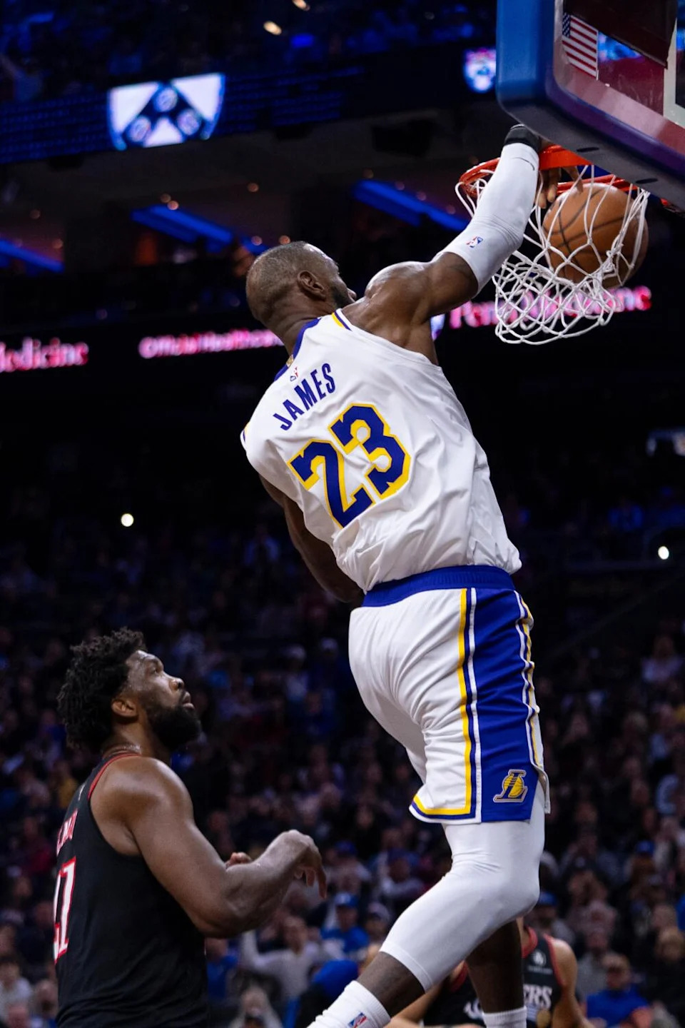 Lakers star LeBron James dunks in front of Philadelphia's Joel Embiid, left, during the first half Sunday.