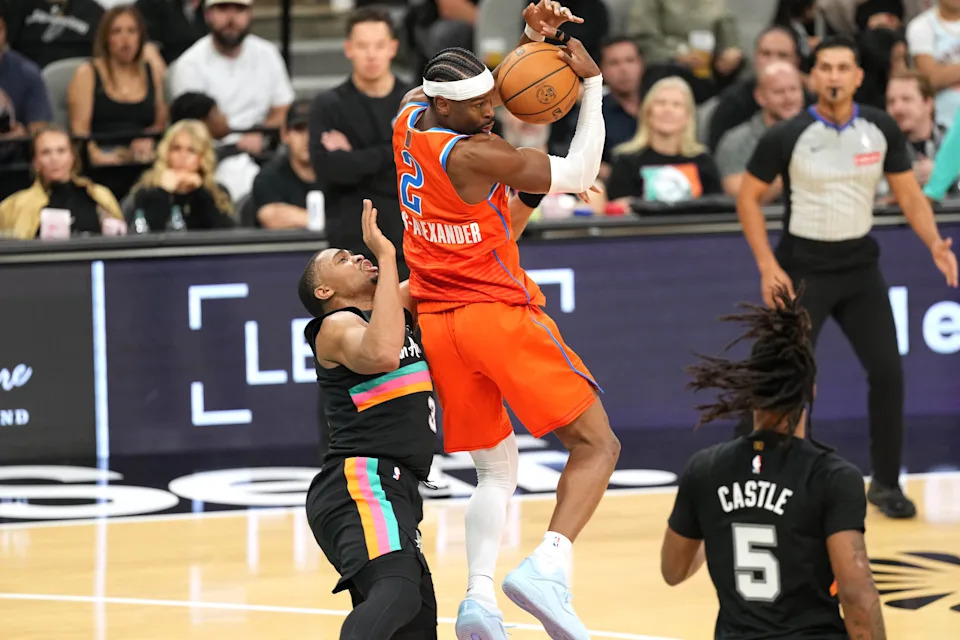 Dec 23, 2025; San Antonio, Texas, USA; Oklahoma City Thunder guard Shai Gilgeous-Alexander (2) grabs a rebound over San Antonio Spurs forward Keldon Johnson (3) during the first half at Frost Bank Center. Mandatory Credit: Scott Wachter-Imagn Images