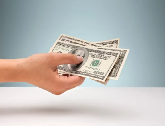 Hand holding US dollar bills.