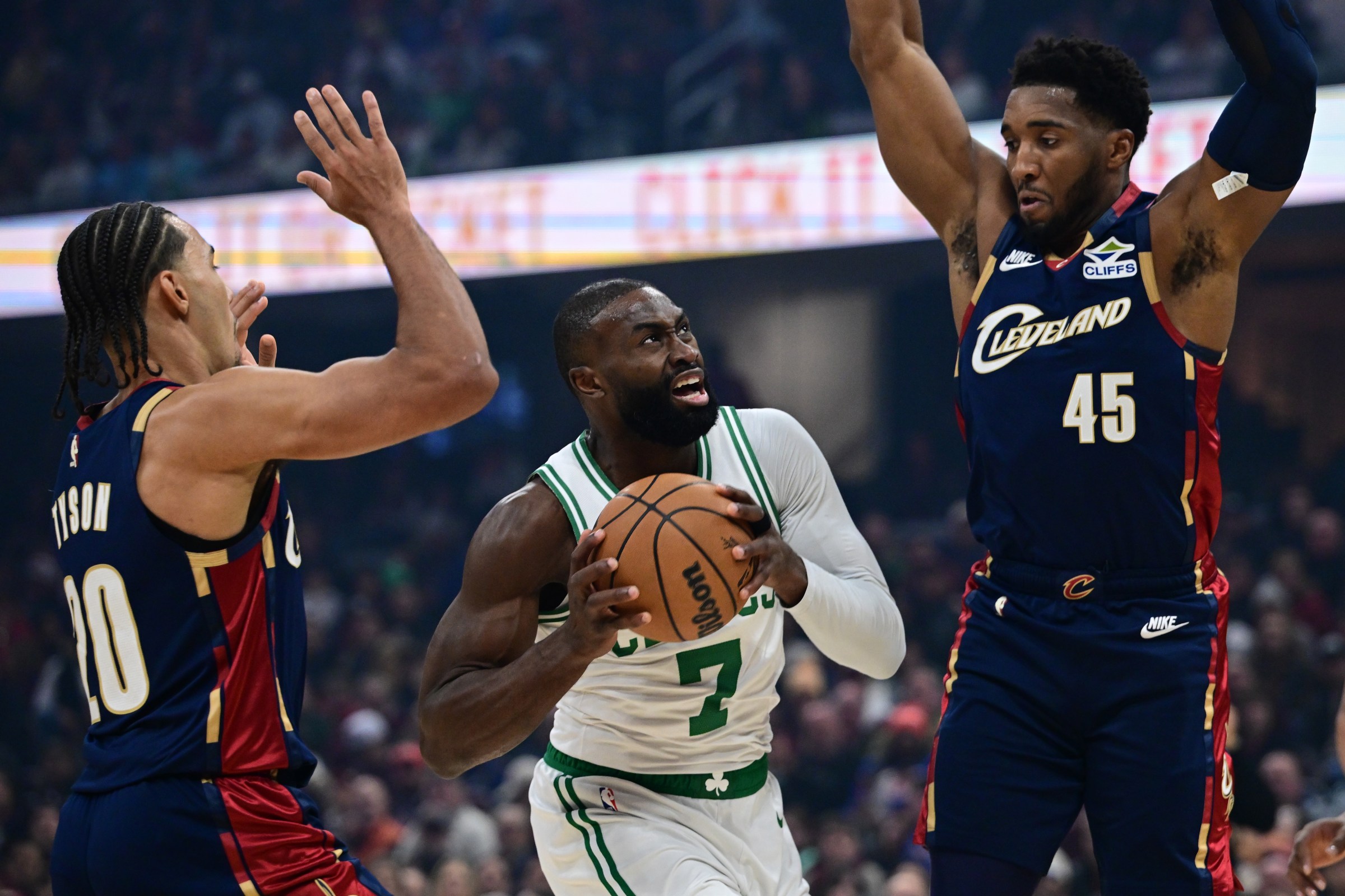 Nov 30, 2025; Cleveland, Ohio, USA; Boston Celtics guard Jaylen Brown (7) goes to the basket against Cleveland Cavaliers guard Donovan Mitchell (45) and guard Jaylon Tyson (20) during the first half at Rocket Arena. Mandatory Credit: David Dermer-Imagn Images