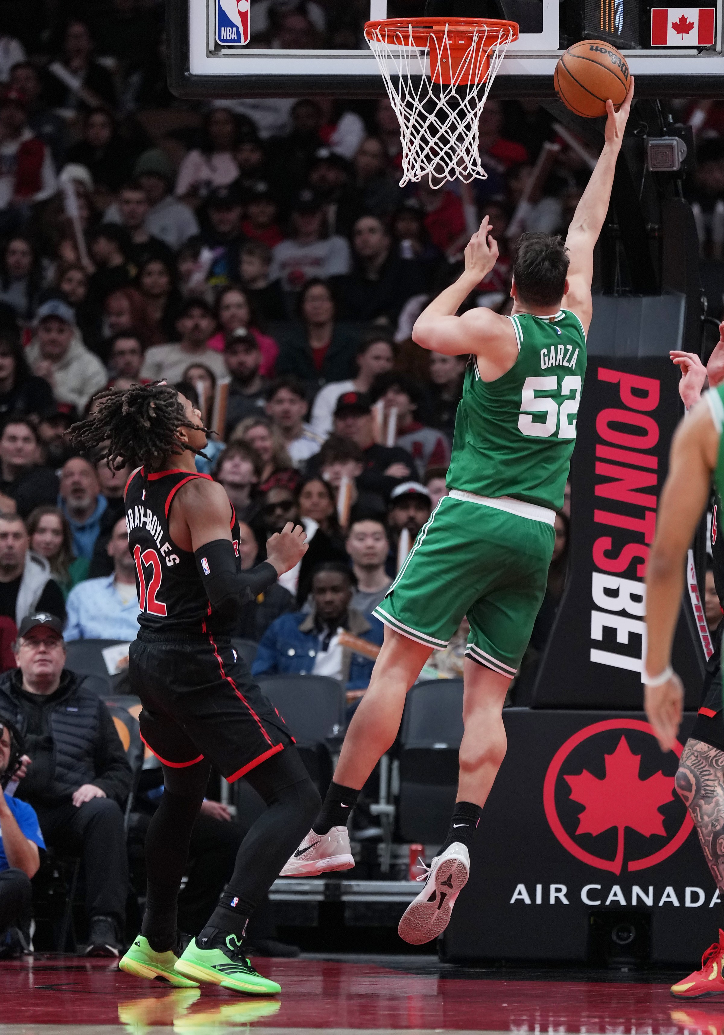 Dec 20, 2025; Toronto, Ontario, CAN; Boston Celtics center Luka Garza (52) drives to the basket over Toronto Raptors forward Collin Murray-Boyles (12) during the third quarter at Scotiabank Arena. Mandatory Credit: Nick Turchiaro-Imagn Images
