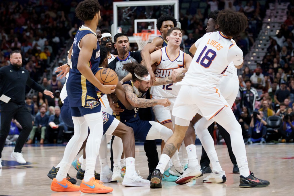 Several basketball players from the Suns and Pelicans engaged in a scrum, with a referee blowing his whistle.