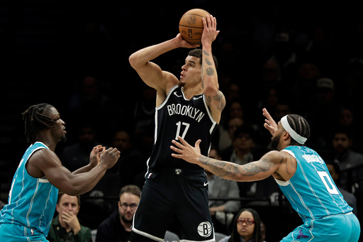 Brooklyn Nets forward Michael Porter Jr. (17) looks to shoot between Charlotte Hornets guard Sion James, left, and forward Miles Bridges (0) during the second half of an NBA basketball game Monday, Dec. 1, 2025, in New York. (AP Photo/Adam Hunger)