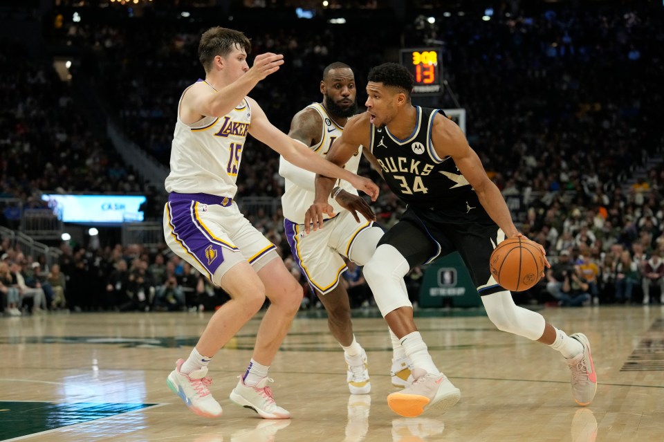 Giannis Antetokounmpo #34 of the Milwaukee Bucks dribbles the ball against Austin Reaves #15 and LeBron James #6 of the Los Angeles Lakers 
