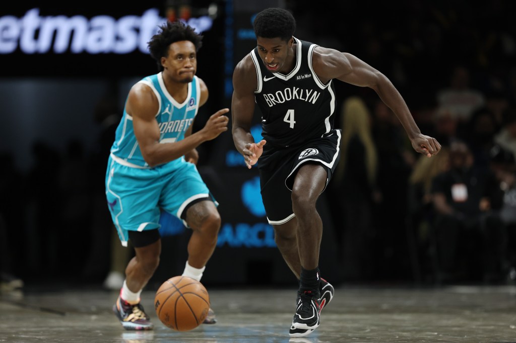 Drake Powell of the Brooklyn Nets grabbing a loose ball as Collin Sexton of the Charlotte Hornets reacts.