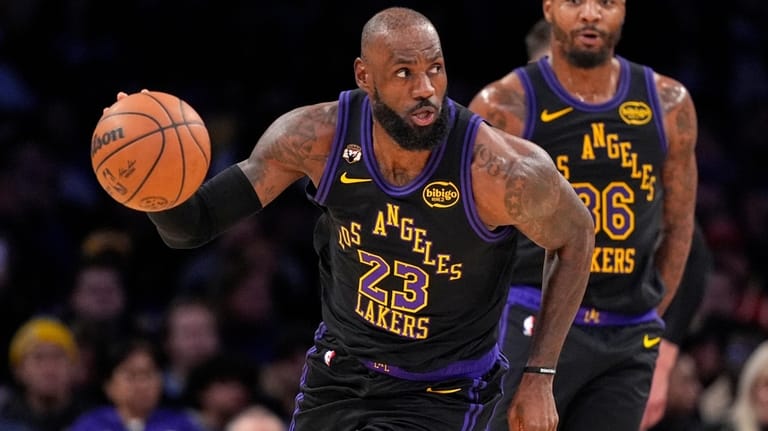 Los Angeles Lakers forward LeBron James, left, dribbles as guard...