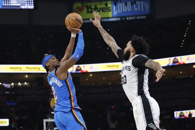 Jan 13, 2026; Oklahoma City, Oklahoma, USA; Oklahoma City Thunder guard Shai Gilgeous-Alexander (2) shoots and scores a basket as San Antonio Spurs forward Julian Champagnie (30) defends during the second half at Paycom Center.