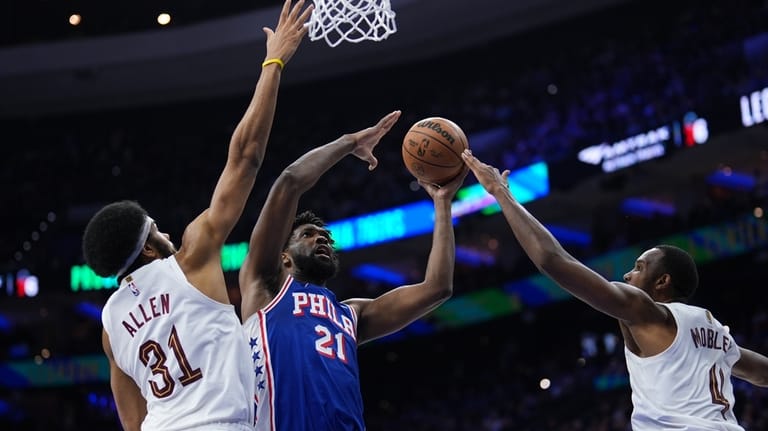 Philadelphia 76ers' Joel Embiid, center, goes up for a shot...