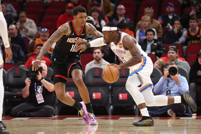 Jan 15, 2026; Houston, Texas, USA; Oklahoma City Thunder guard Luguentz Dort (5) drives with the ball as Houston Rockets forward Jabari Smith Jr. (10) defends during the first quarter at Toyota Center. Mandatory Credit: Troy Taormina-Imagn Images