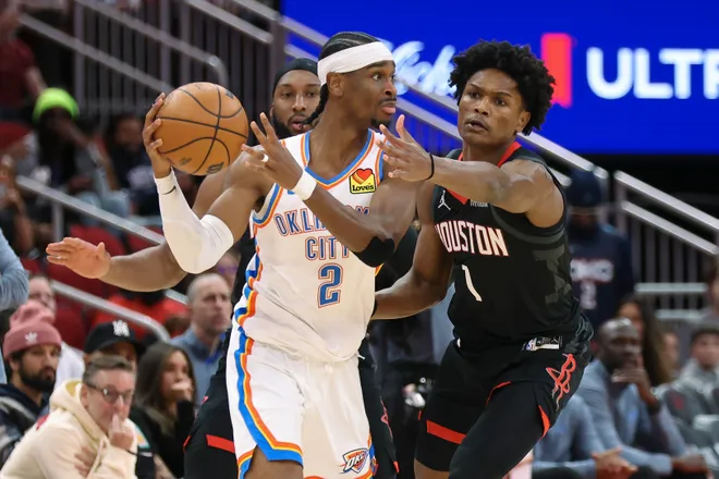 Jan 15, 2026; Houston, Texas, USA; Oklahoma City Thunder guard Shai Gilgeous-Alexander (2) looks to pass the ball as Houston Rockets guard Amen Thompson (1) defends during the first quarter at Toyota Center. Mandatory Credit: Troy Taormina-Imagn Images