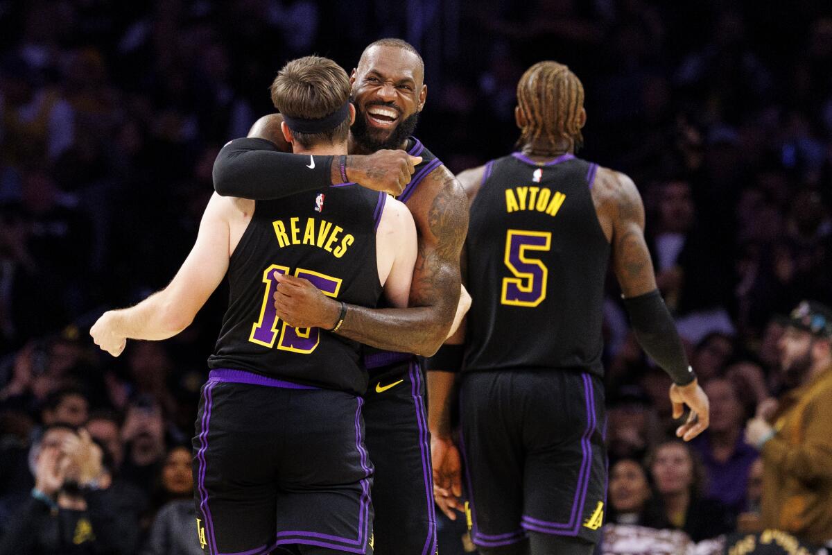 Lakers forward LeBron James hugs teammate Austin Reaves on the court
