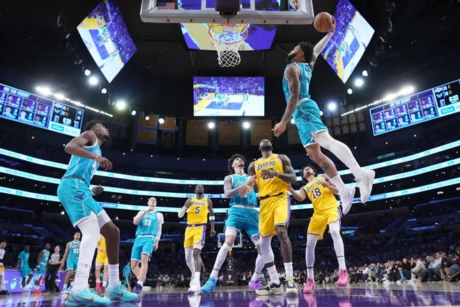Jan 15, 2026; Los Angeles, California, USA; Charlotte Hornets forward Miles Bridges (0) dunks the ball against Los Angeles Lakers forward LeBron James (23) and guard Kobe Bufkin (18) in the first half at Crypto.com Arena.