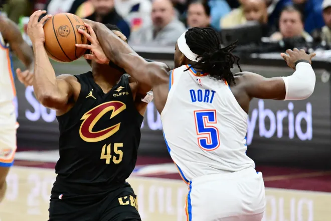Jan 19, 2026; Cleveland, Ohio, USA; Cleveland Cavaliers guard Donovan Mitchell (45) drives to the basket against Oklahoma City Thunder guard Luguentz Dort (5) during the second half at Rocket Arena. Mandatory Credit: Ken Blaze-Imagn Images