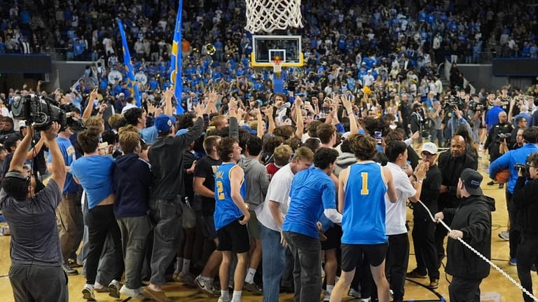 UCLA fans storm the court after the team defeated Purdue...