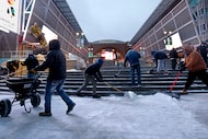 Workers clear snow in front of American Airlines Center before an NBA basketball game...
