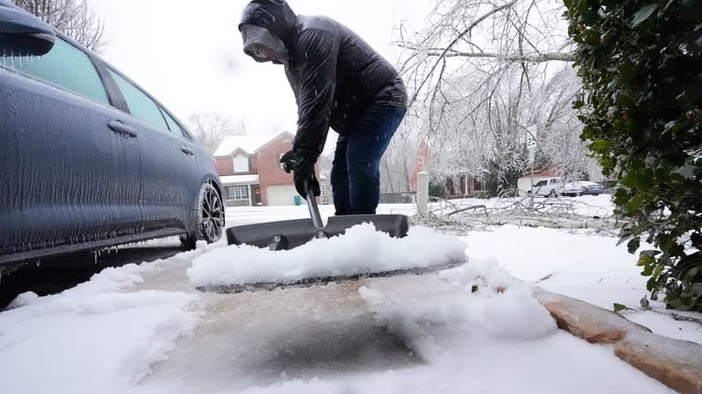 David Bentley shovels ice and snow from his driveway during...
