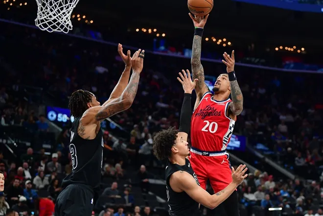 Jan 25, 2026; Inglewood, California, USA; Los Angeles Clippers forward John Collins (20) shoots against Brooklyn Nets forward Jalen Wilson (22) and center Nic Claxton (33) during the first half at Intuit Dome.
