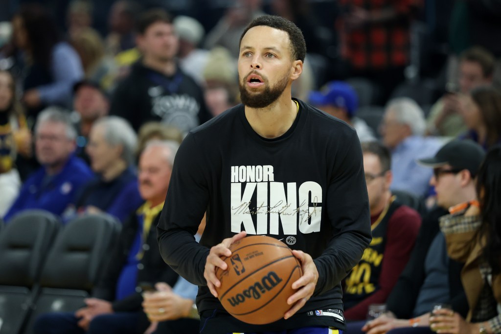 Stephen Curry holding a basketball at a Golden State Warriors game.
