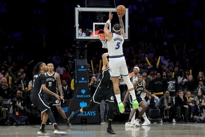 Jan 7, 2026; Brooklyn, New York, USA; Orlando Magic forward Paolo Banchero (5) shoots an overtime game-winning three point shot against Brooklyn Nets forward Michael Porter Jr. (17) as time expires at Barclays Center.