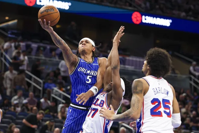 Jan 9, 2026; Orlando, Florida, USA; Orlando Magic forward Paolo Banchero (5) drives to the basket over Philadelphia 76ers guard Vj Edgecombe (77) in the third quarter at Kia Center.