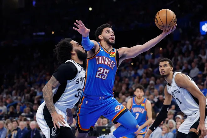 Jan 13, 2026; Oklahoma City, Oklahoma, USA; Oklahoma City Thunder guard Ajay Mitchell (25) goes to the basket beside San Antonio Spurs forward Julian Champagnie (30) during the second half at Paycom Center. Mandatory Credit: Alonzo Adams-Imagn Images