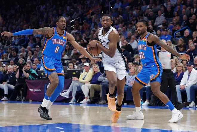Jan 13, 2026; Oklahoma City, Oklahoma, USA; San Antonio Spurs guard De'aaron Fox (4) drives between Oklahoma City Thunder guard/forward Jalen Williams (8) and guard Cason Wallace (22) during the second quarter at Paycom Center. Mandatory Credit: Alonzo Adams-Imagn Images
