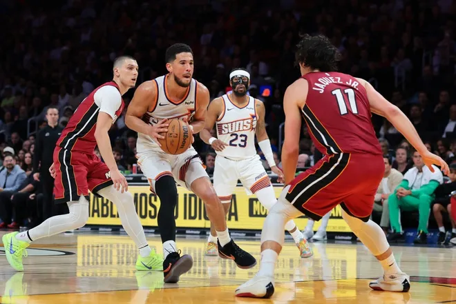 Jan 13, 2026; Miami, Florida, USA; Phoenix Suns guard Devin Booker (1) drives to the basket against Miami Heat guard Tyler Herro (14) and forward Jaime Jaquez Jr. (11) during the third quarter at Kaseya Center.