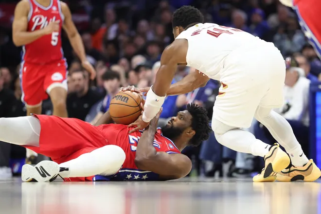 Jan 16, 2026; Philadelphia, Pennsylvania, USA; Philadelphia 76ers center Joel Embiid (21) grabs a loose ball against Cleveland Cavaliers guard Donovan Mitchell (45) during the fourth quarter at Xfinity Mobile Arena. Mandatory Credit: Bill Streicher-Imagn Images