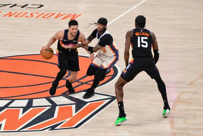 Jan 17, 2026; New York, New York, USA; Phoenix Suns guard Devin Booker (1) tries to dribble past New York Knicks guard Jordan Clarkson (00) during the second half at Madison Square Garden.
