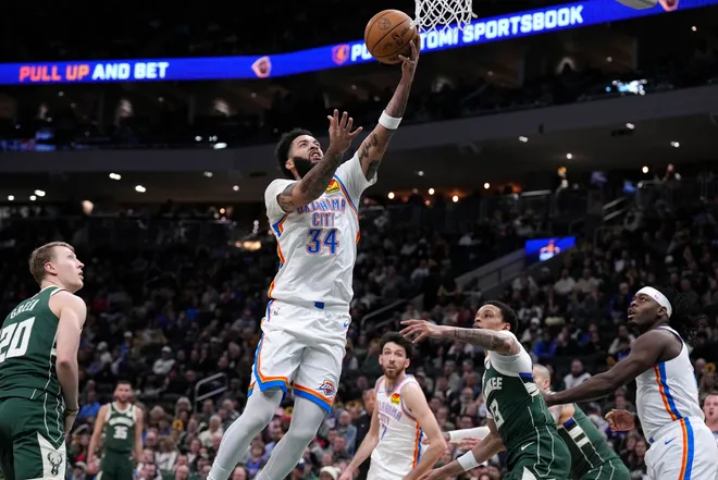 Jan 21, 2026; Milwaukee, Wisconsin, USA; Oklahoma City Thunder guard/forward Kenrich Williams (34) drives to the basket against Milwaukee Bucks guard Ryan Rollins (13) in the first half at Fiserv Forum. Mandatory Credit: Michael McLoone-Imagn Images