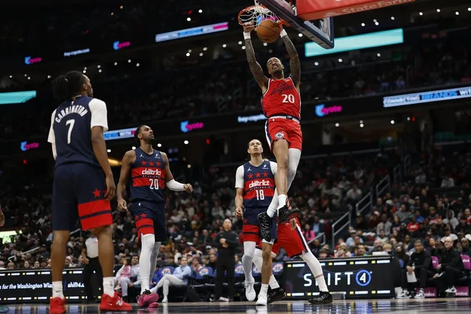 Jan 19, 2026; Washington, District of Columbia, USA; LA Clippers forward John Collins (20) dunks the ball as Washington Wizards center Alex Sarr (20) and Wizards forward Kyshawn George (18) look on in the second half at Capital One Arena.