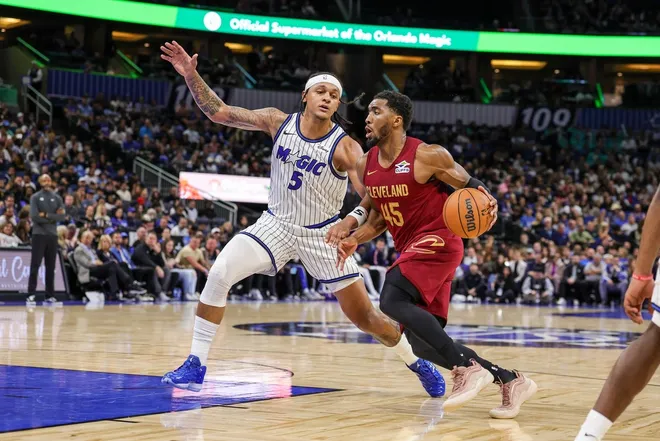 Jan 24, 2026; Orlando, Florida, USA; Cleveland Cavaliers guard Donovan Mitchell (45) drives around Orlando Magic forward Paolo Banchero (5) during the second half at Kia Center.